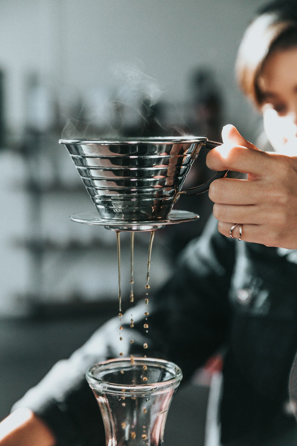 persona sosteniendo una taza de acero inoxidable gris con humo