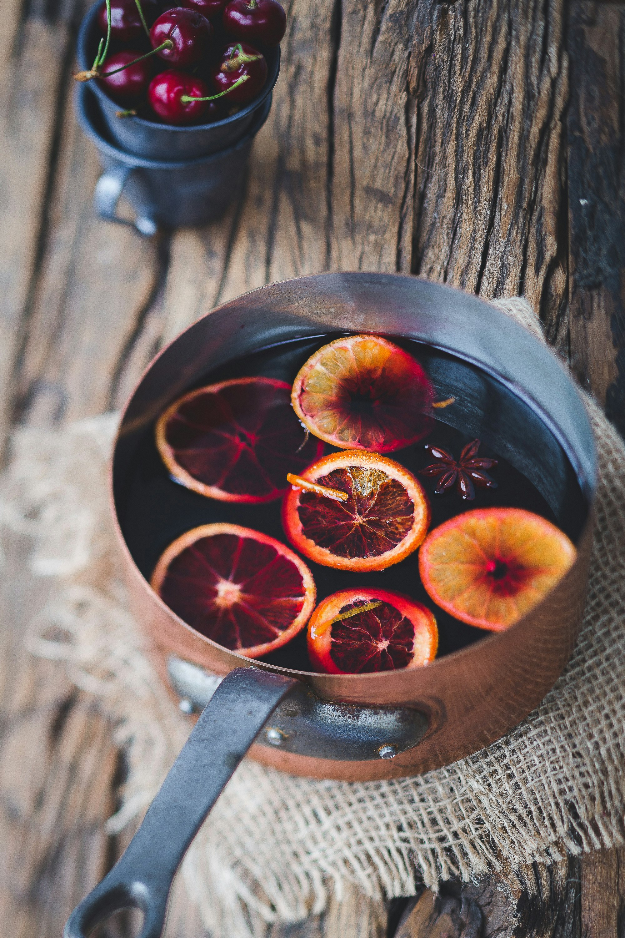 Fruits and spices in a pot of slow cooked sangria for a Christmas cocktail.