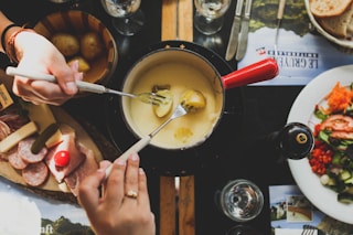 two person holding fork dipping food on sauce