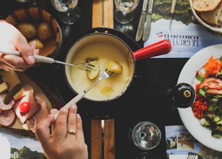 two person holding fork dipping food on sauce