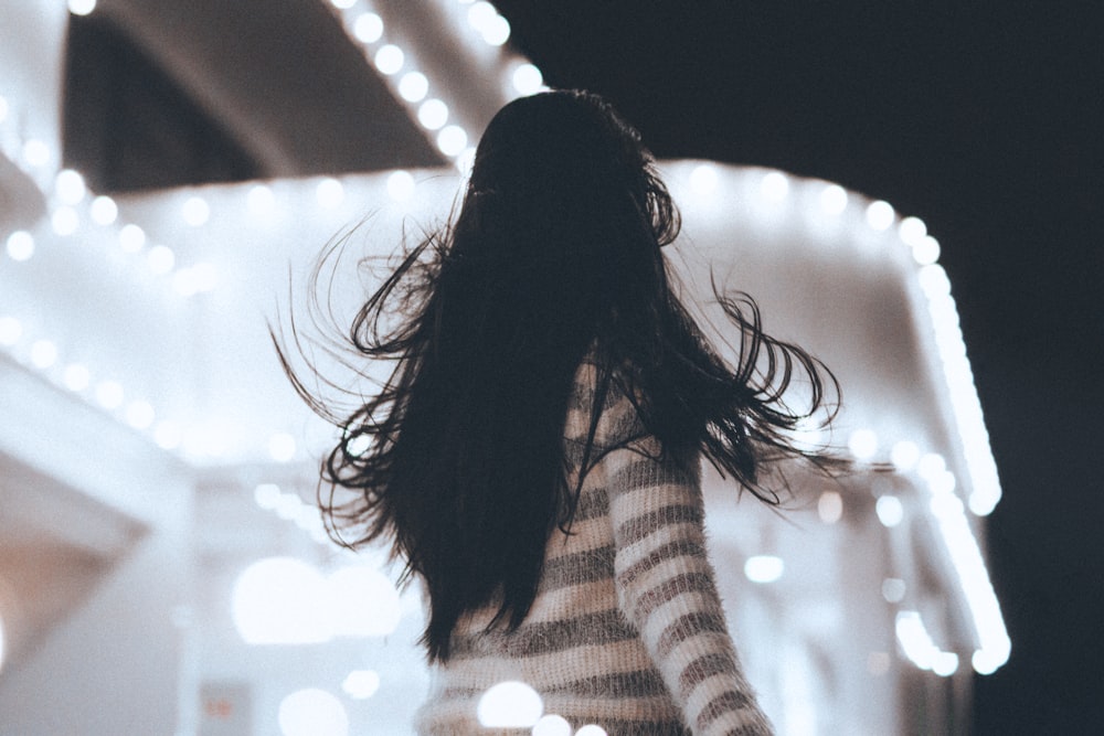 shallow focus photography of woman facing white concrete structure during nighttime