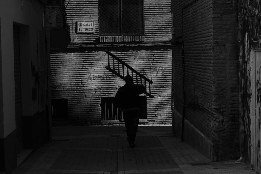 grayscale photography of man carrying ladder