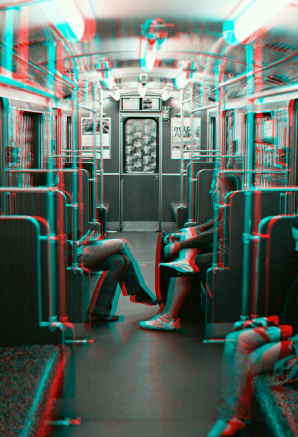 Foto in scala di grigi di due persone una di fronte all'altra mentre sono sedute all'interno del treno