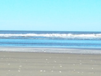 A tranquil morning scene of gentle waves meeting the sandy shore at Kaia by the Beach.