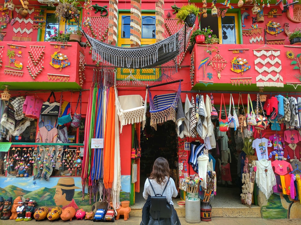 femme se tient devant la maison rouge avec des sacs en tissu