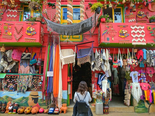 woman stand in front of red house with fabric bags in Ráquira Colombia