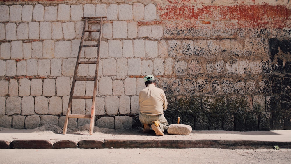 man in beige dress shirt sitting on wall