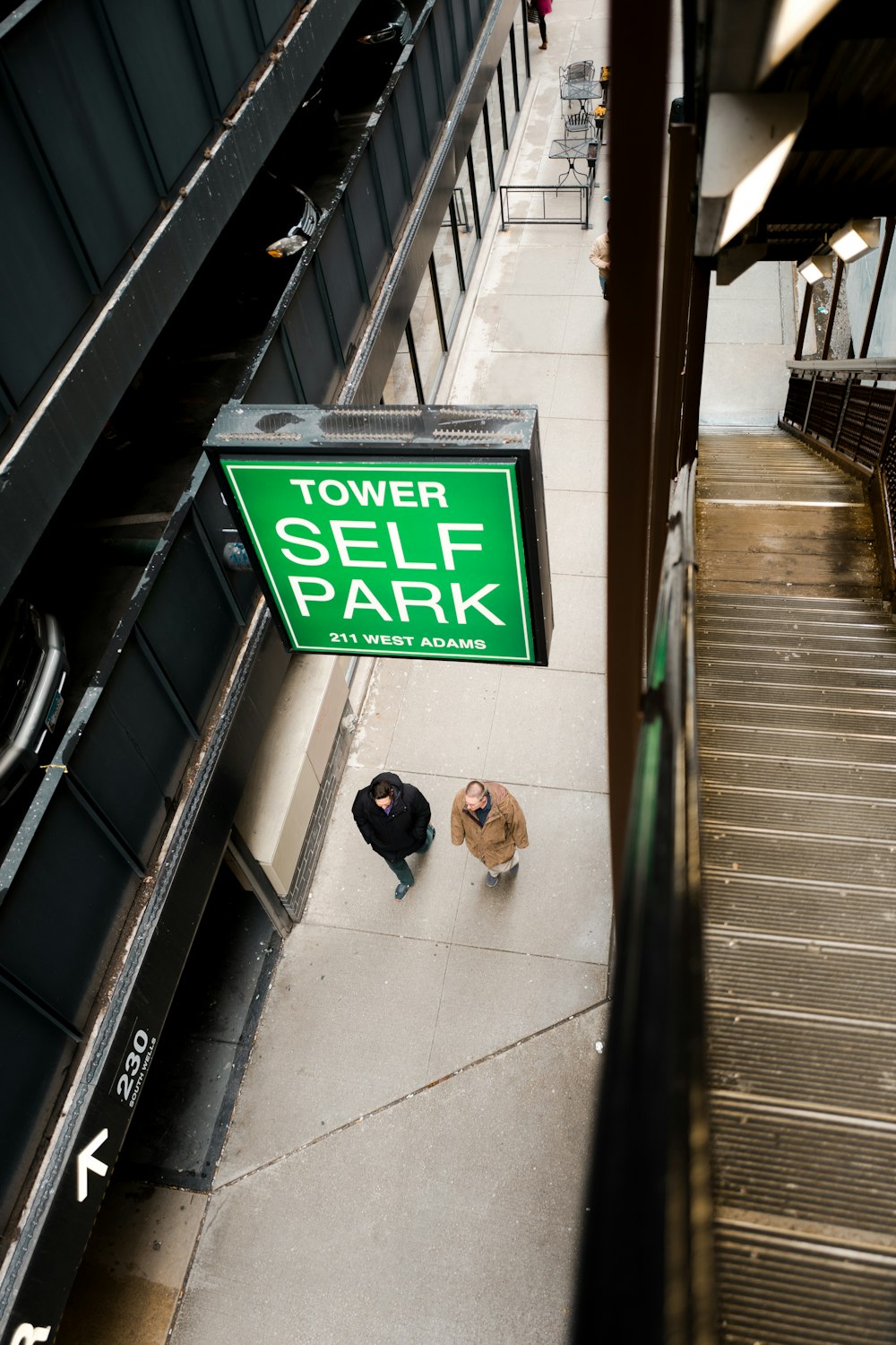 two person's walking underneath Tower Self Park signage