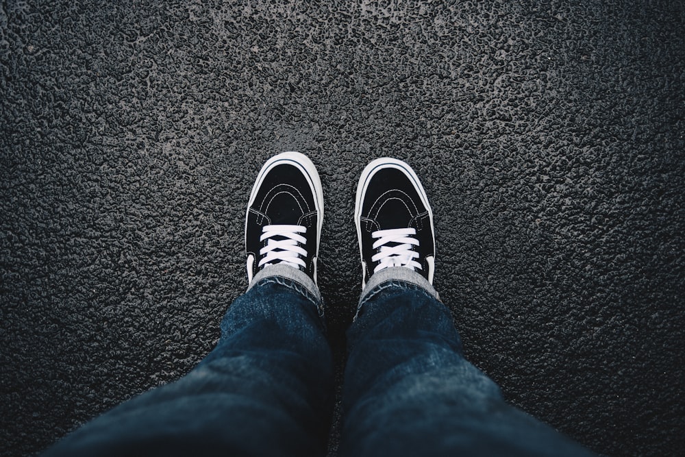 person wearing black sneakers standing on black surface