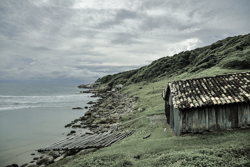 brown house beside ocean under cloudy sky during daytime