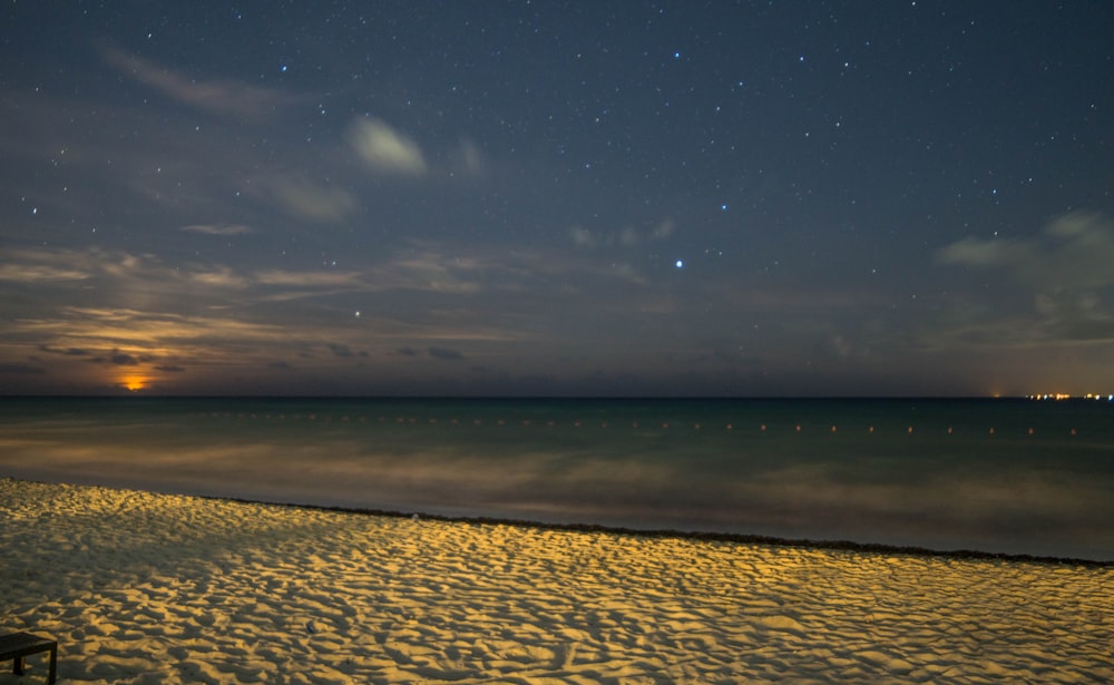 white sand beside body of water during night time