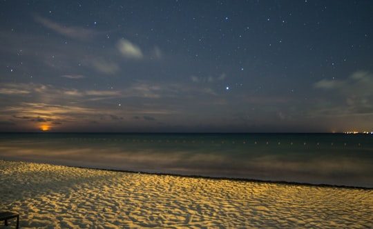 white sand beside body of water during night time in Cancún Mexico
