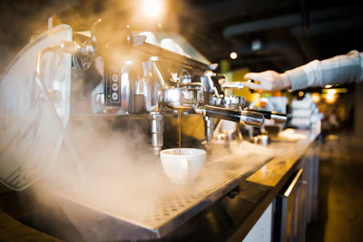 Elegant barista pouring espresso with emerald green and gold accents in a modern café setting.