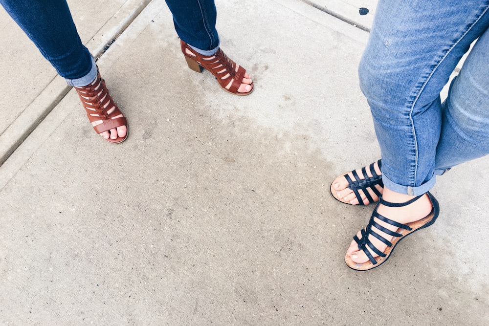 two woman wearing black and brown strappy sandals