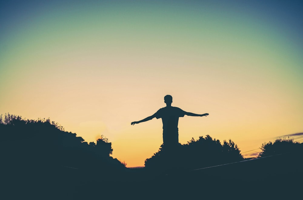 silhouette photography of man raising arms