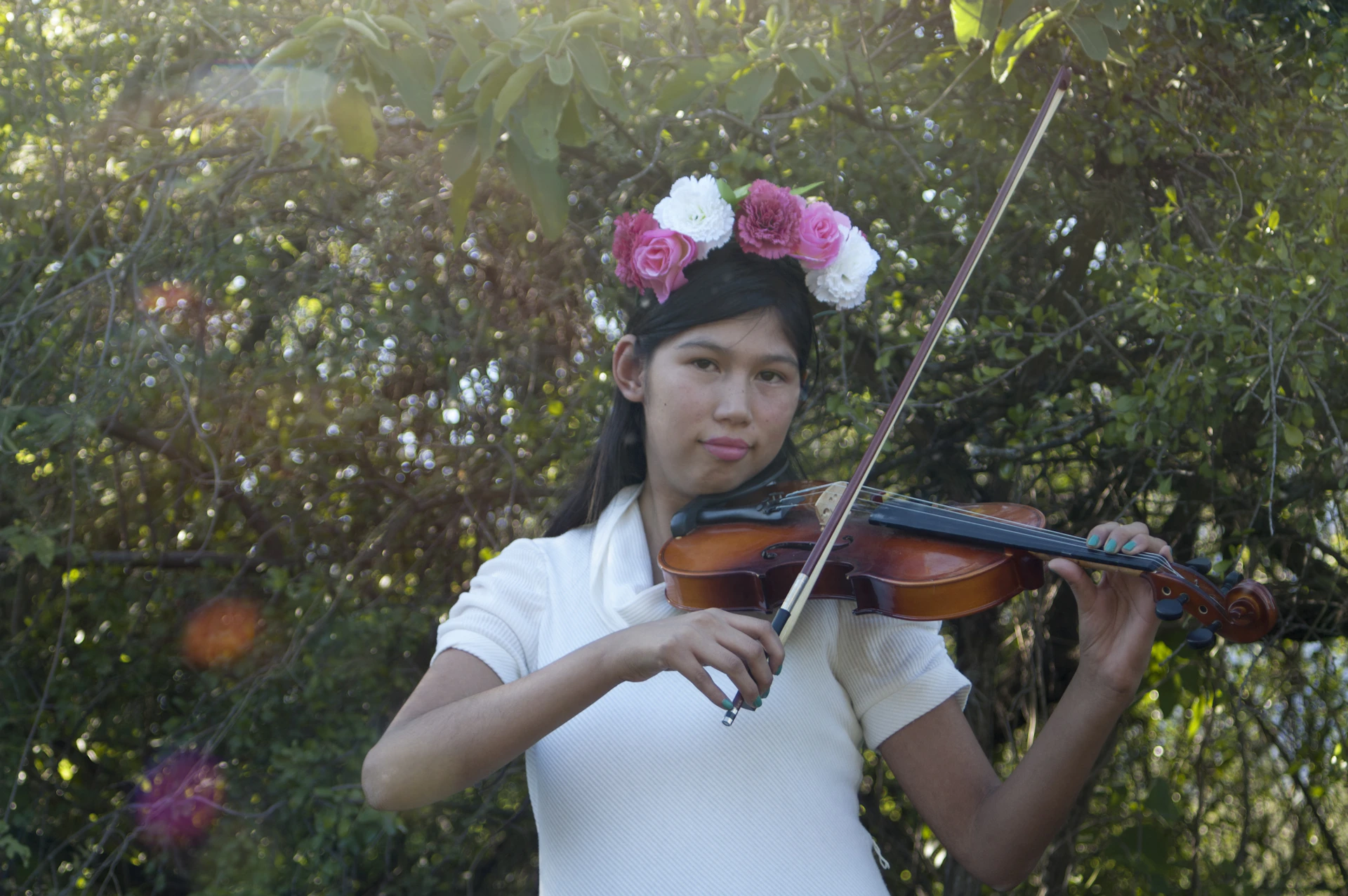 A talented violinist passionately performing during a romantic wedding ceremony in a sunlit garden.