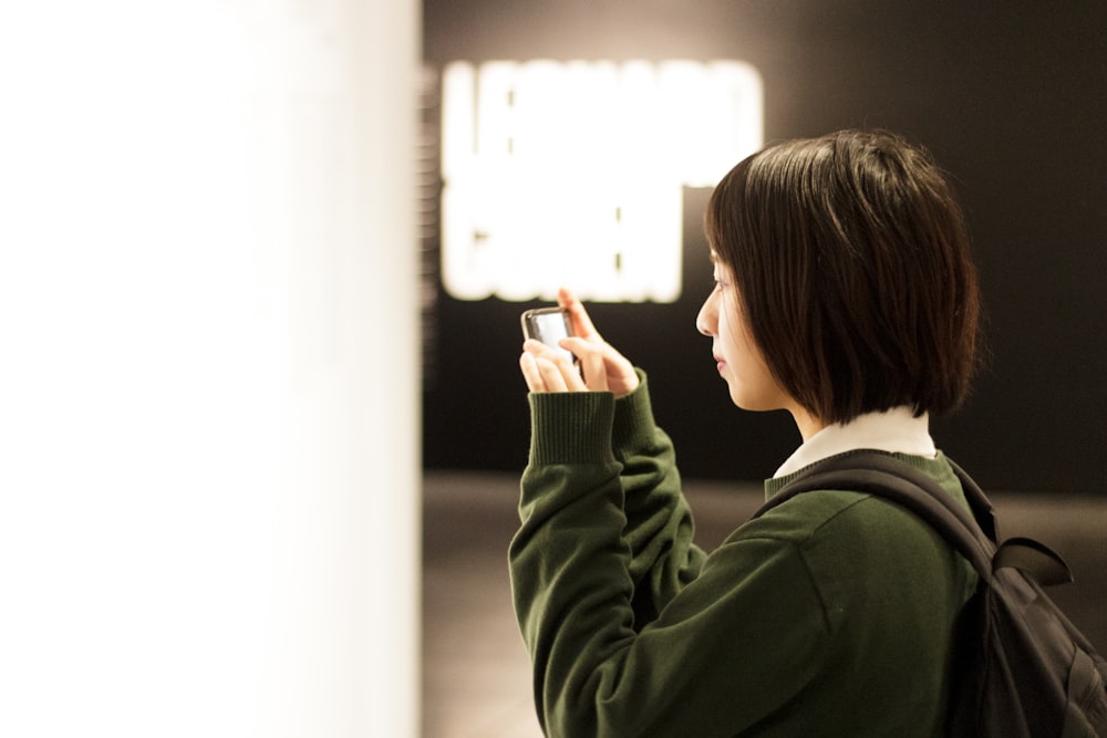 woman holding smartphone while taking picture