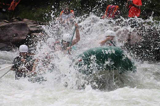 A raft crew rowing through whitewater, seen from behind