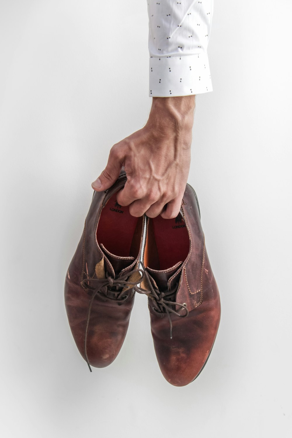 person holding pair of brown leather shoes