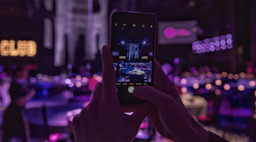 Close-up of hands holding smartphones showing the nochevota voting app interface with nightclub options.