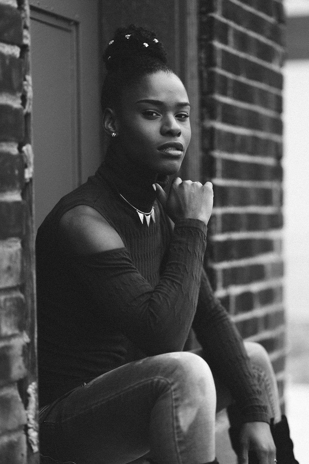 woman sitting on pavement on grayscale photography