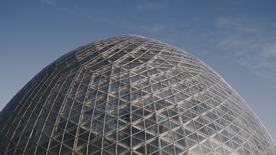 A vast transparent dome covering a green agricultural field under a clear blue sky.