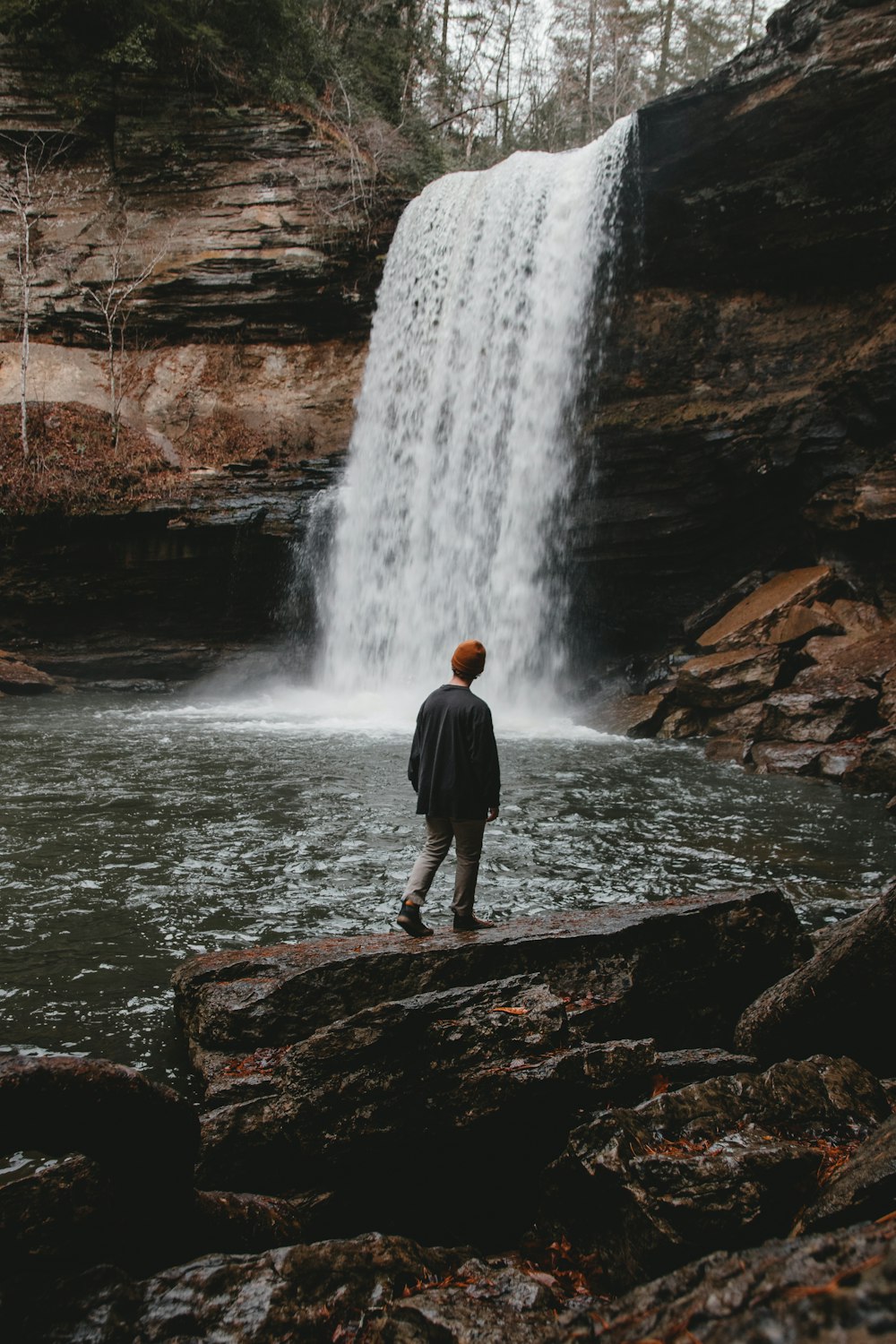 homme debout sur la pierre face à des cascades