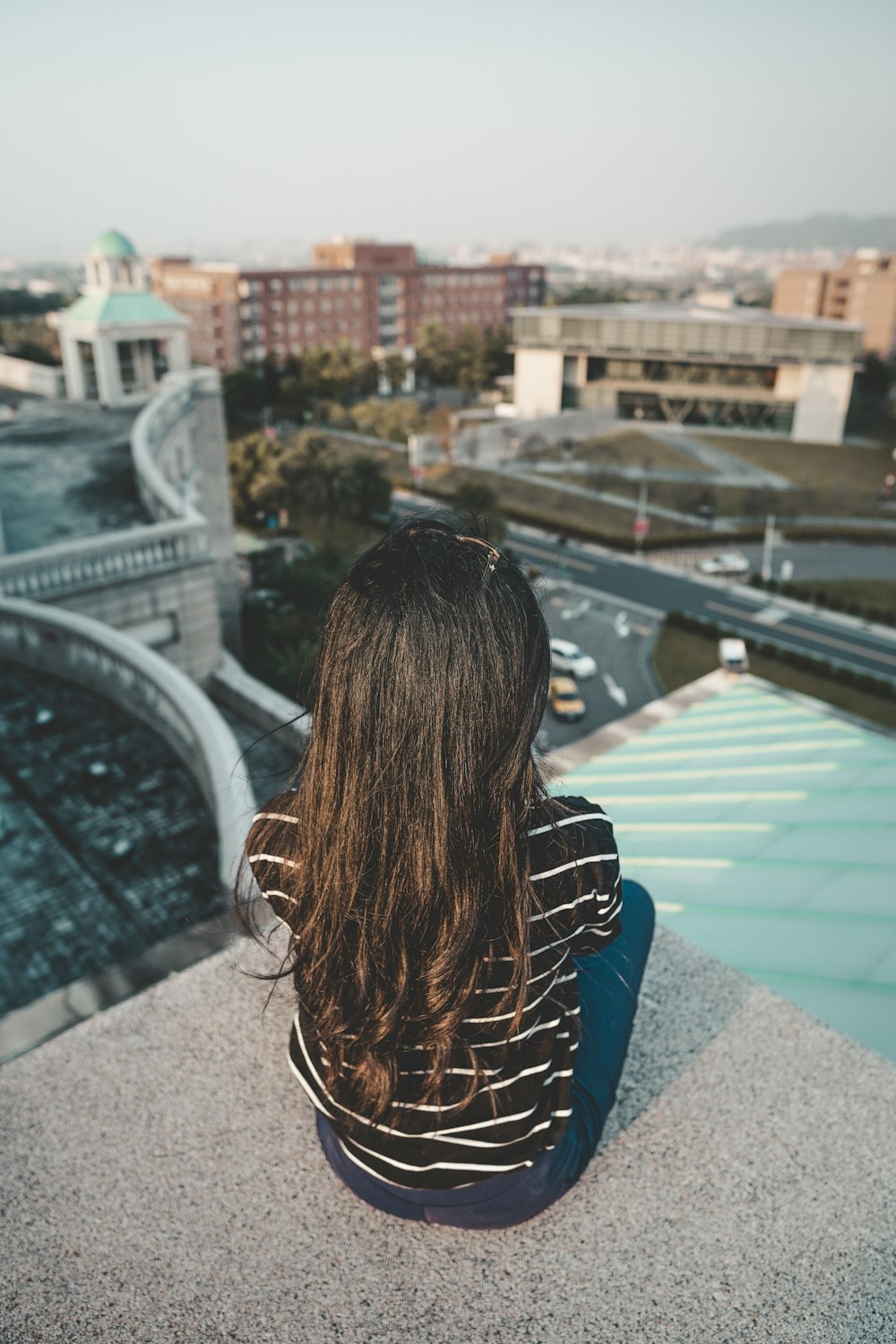 shallow focus photography of woman sitting on concrete pavement