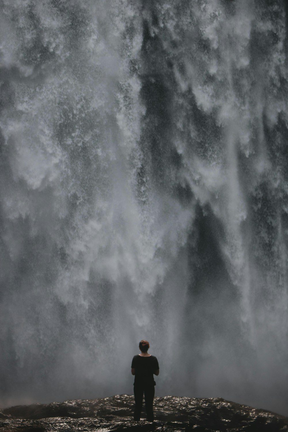 femme debout devant des chutes d’eau pendant la journée