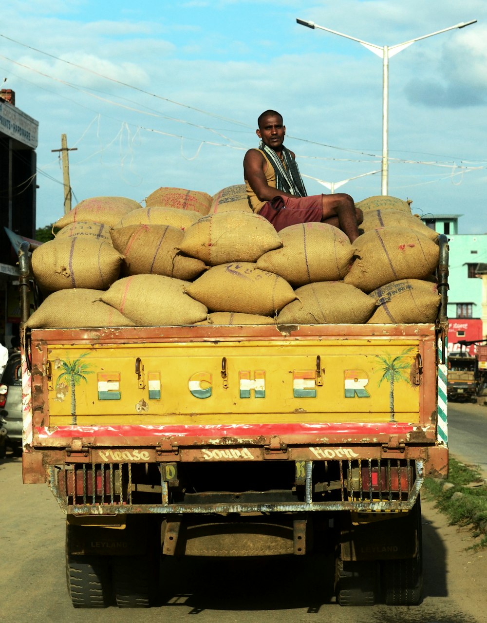 man sitting on sack in dumptruck near street light under cloudy sky