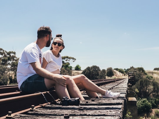 man and woman sitting on train rail in Currency Creek Australia