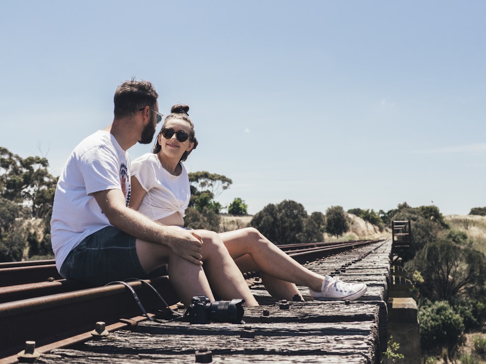 man and woman sitting on train rail