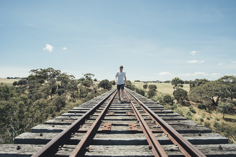 man walking on train rail track during day time
