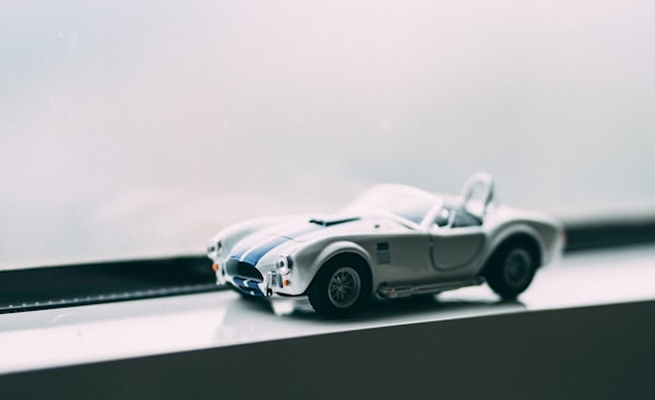 A toy car sitting on a window shelf