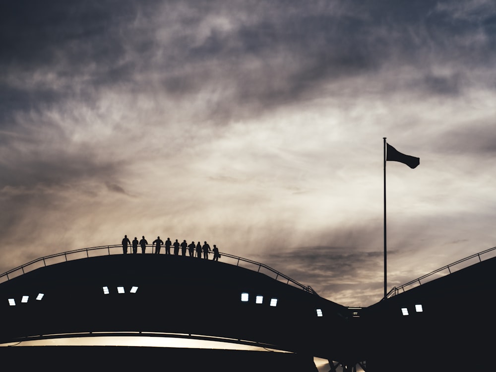 foto di silhouette di persone in piedi sul ponte