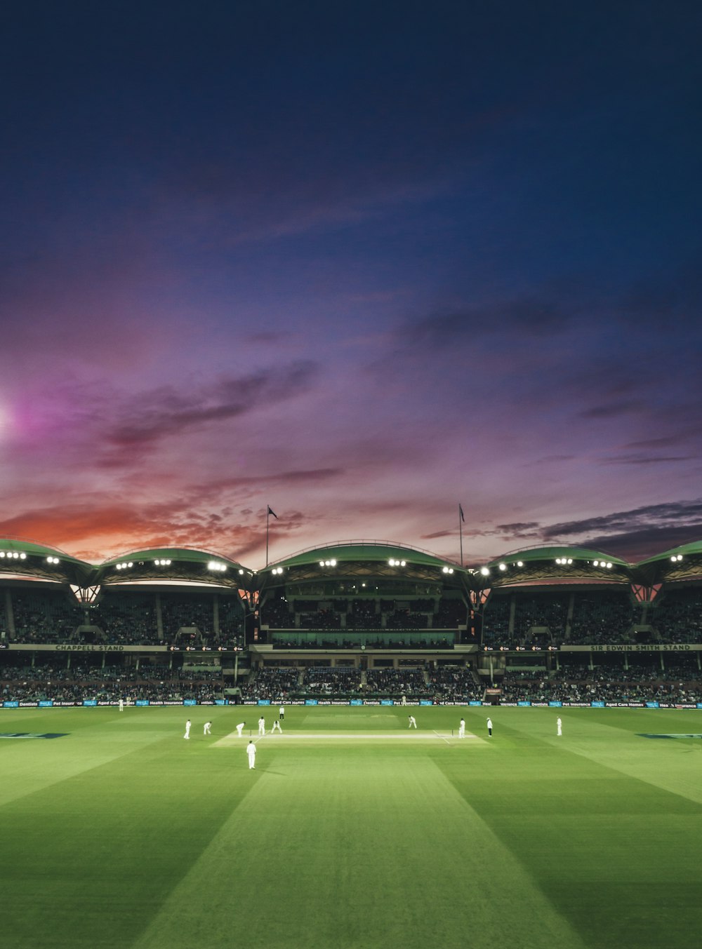 Menschen, die ein Cricket-Spiel bei Sonnenuntergang beobachten