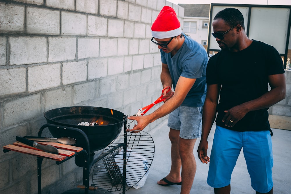 two man standing beside the charcoal grill