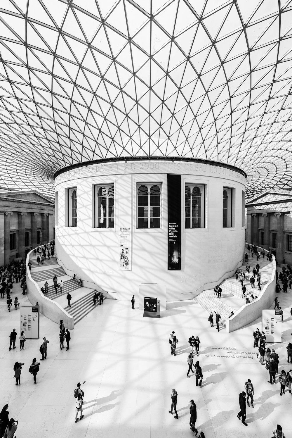 Photographie en niveaux de gris de personnes à l’intérieur d’un bâtiment