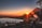 A happy family enjoying a lakeside picnic with mountains in the background at sunset.