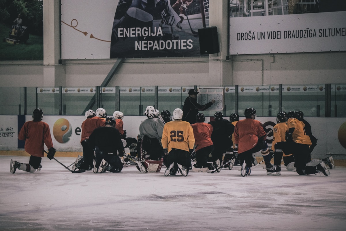 Hockey coach addressing players in a huddle on the ice — the Andrew Sherman case is changing how coaches and rinks think about liability