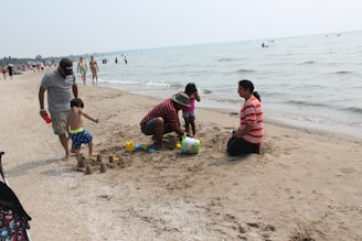 A family happily building sandcastles on a sunny Cancun beach with turquoise waters.