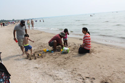 A family building sandcastles on a vibrant Caribbean beach under a bright blue sky.