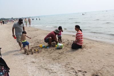 Children building sandcastles while parents relax nearby under colorful umbrellas