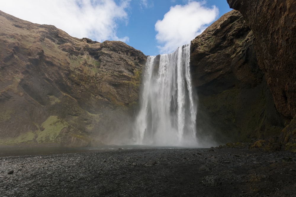 waterfalls on rock formation under cloudy sky during daytime