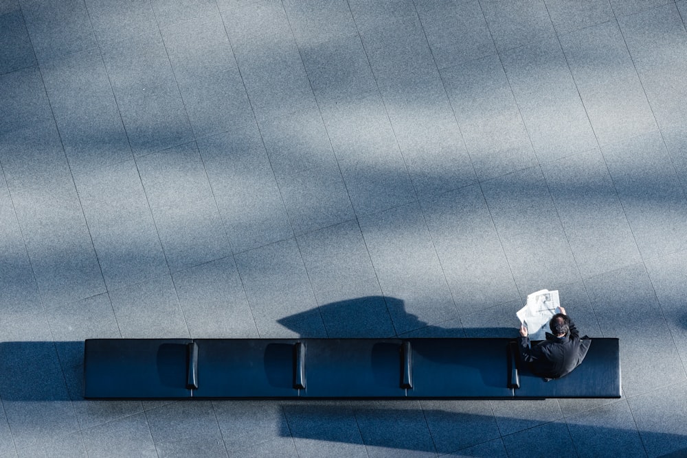 person sitting on black bench reading newspaper