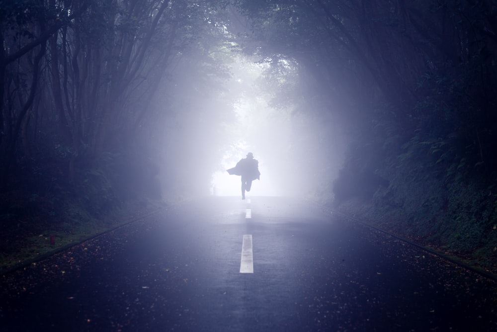 person running road between trees