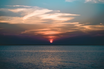 A tranquil sunset over the ocean, casting warm colors in the sky.