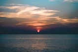 A peaceful sunset over the ocean, casting warm colors in the sky.