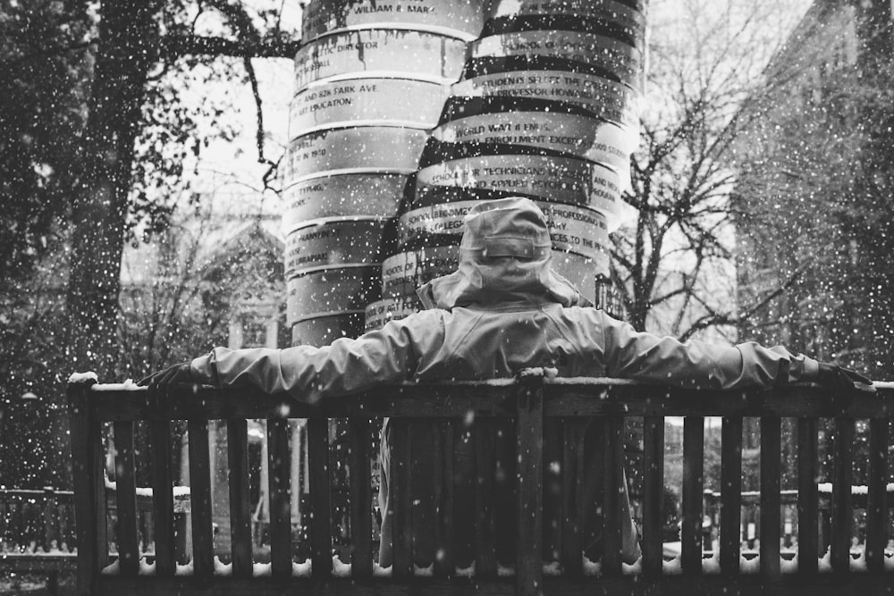 grayscale photography of person sitting on bench