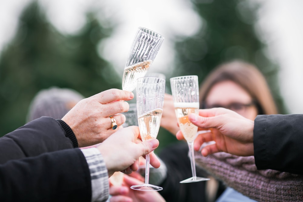 people holding clear champagne glasses